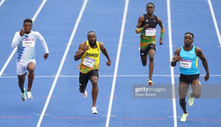 Sean Safo-Antwi of Ghana and Stephan Charles of St Lucia compete during the Men's 100m Round 1 heats